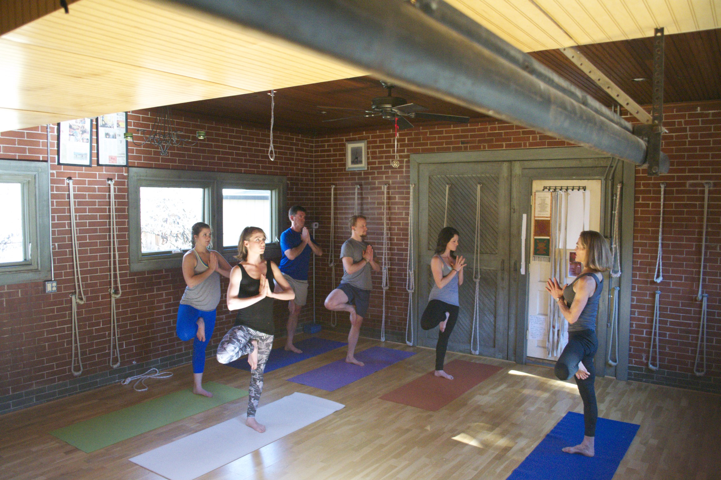 Group tree pose class showing the beautiful Park Hill Yoga studio space with exposed brick and natural light